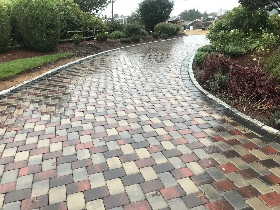 Curved paver driveway in mixed colors, after rain