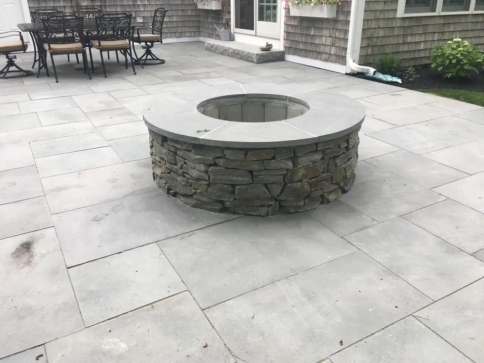 Fieldstone fire pit with a bluestone cap on a bluestone patio