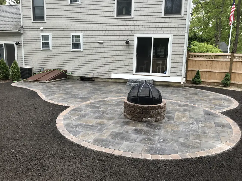 Round fieldstone fire pit on a circular paver patio with a border course