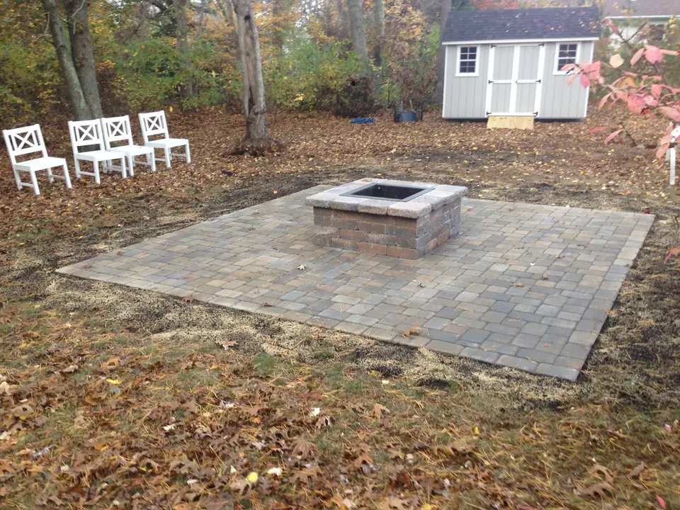 Square paver fire pit on its own pad in the woods