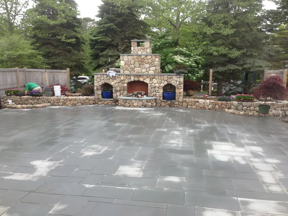 Fieldstone outdoor fireplace with wood niches, at the end of a large bluestone patio