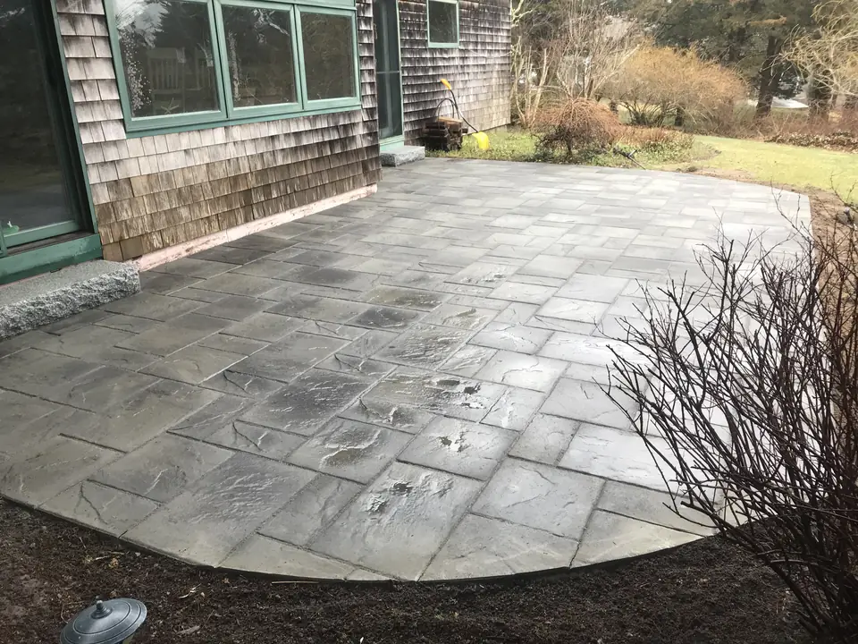 Curved bluestone patio along a shingled house