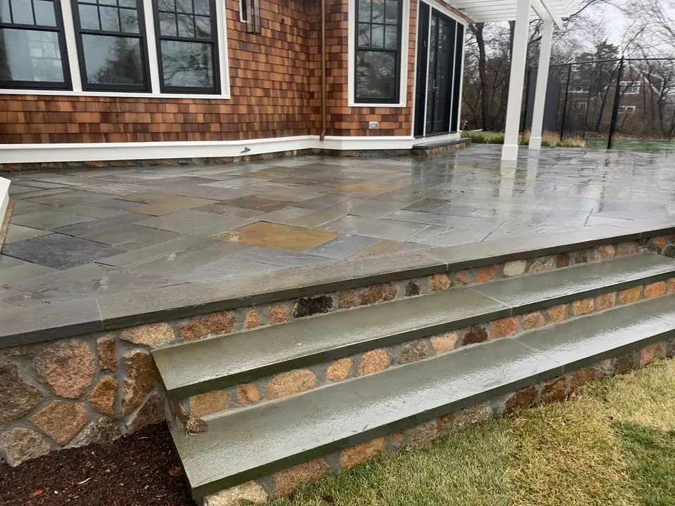 Raised bluestone patio with a fieldstone face and bluestone steps