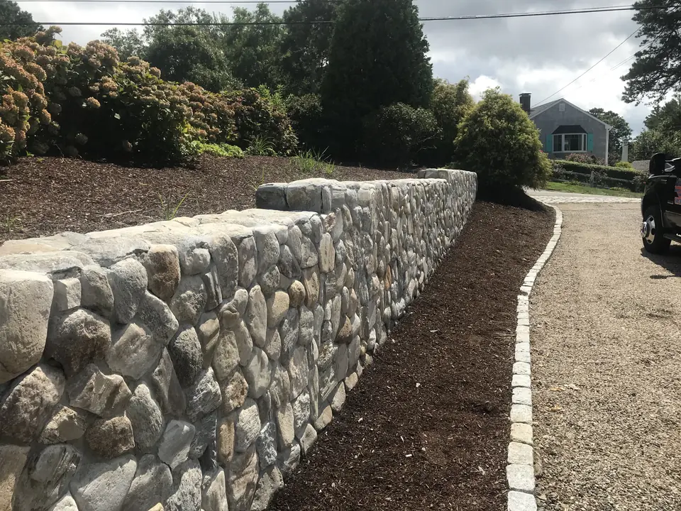 Fieldstone wall along a driveway with a cobblestone edge