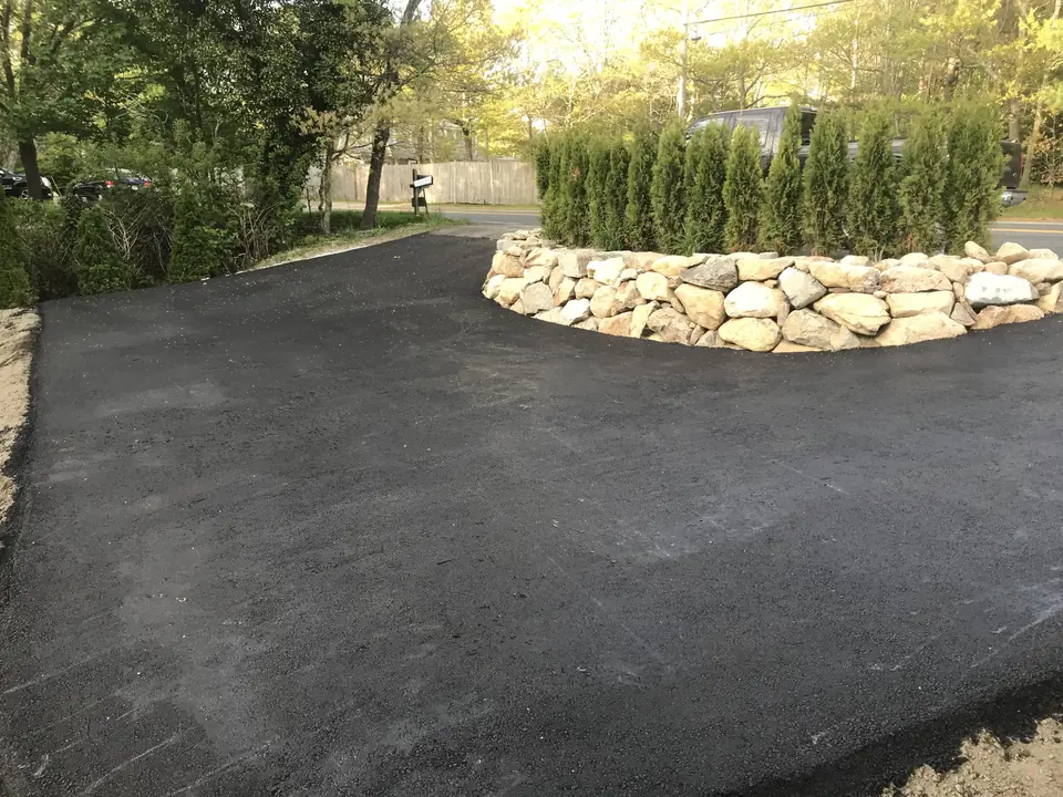 Low fieldstone planter wall at the end of a driveway