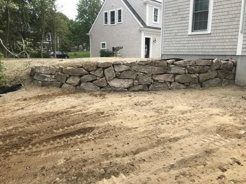 Low fieldstone wall on new grade, in front of the house