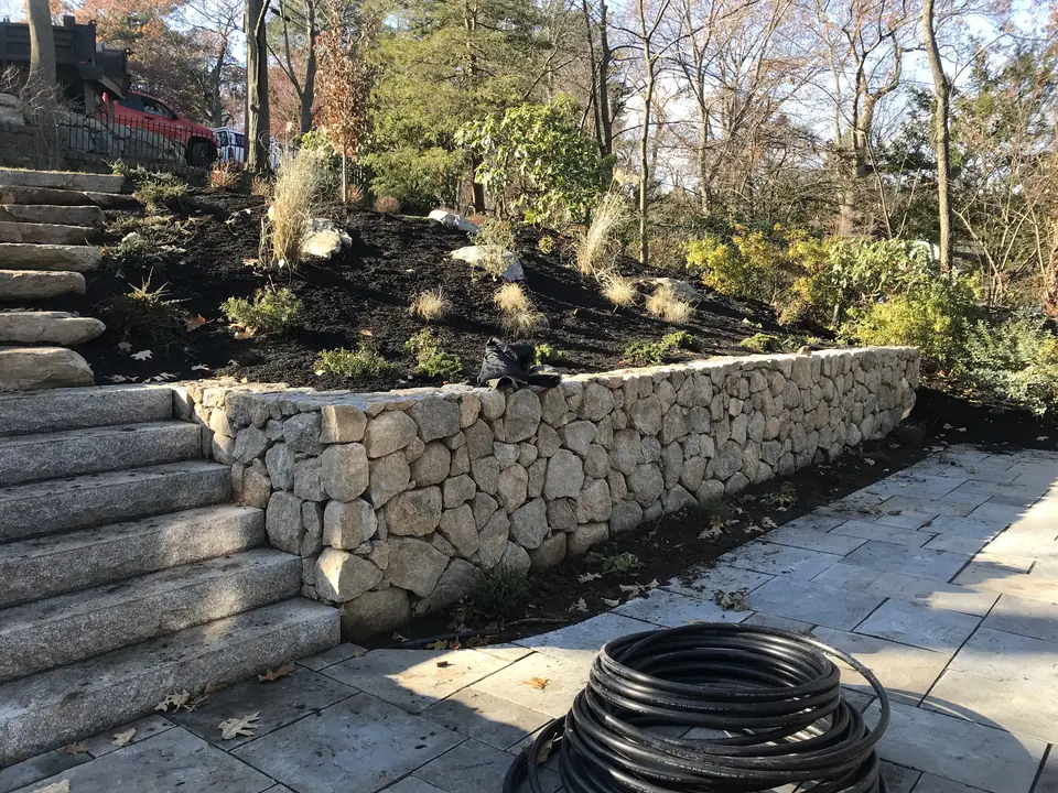 Fieldstone retaining wall with granite steps and a bluestone landing